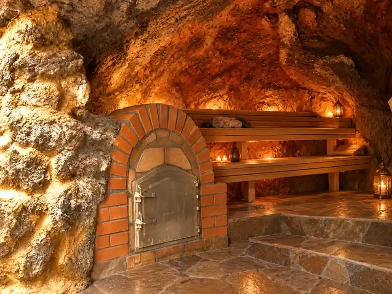 Wellness Retreat Kanaren: Holzofen und warm beleuchteter Innenraum einer besonderen Eco-Höhlensauna auf La Palma.