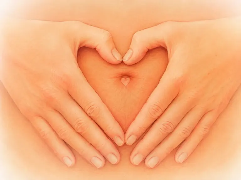 Hände in Herzform auf dem Bauch als Symbol für Darmgesundheit, Detox und Heilfasten.